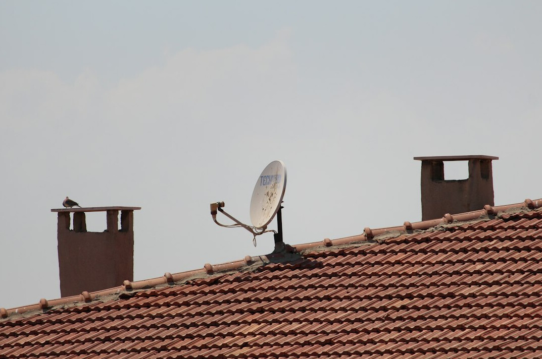 Satellite dish on a rooftop against the sky
